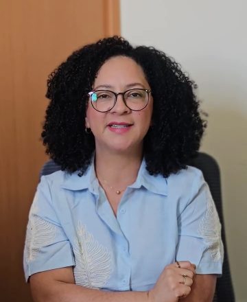 Suely Gusmão, psicóloga, de camisa azul-clara, sentada no consultório